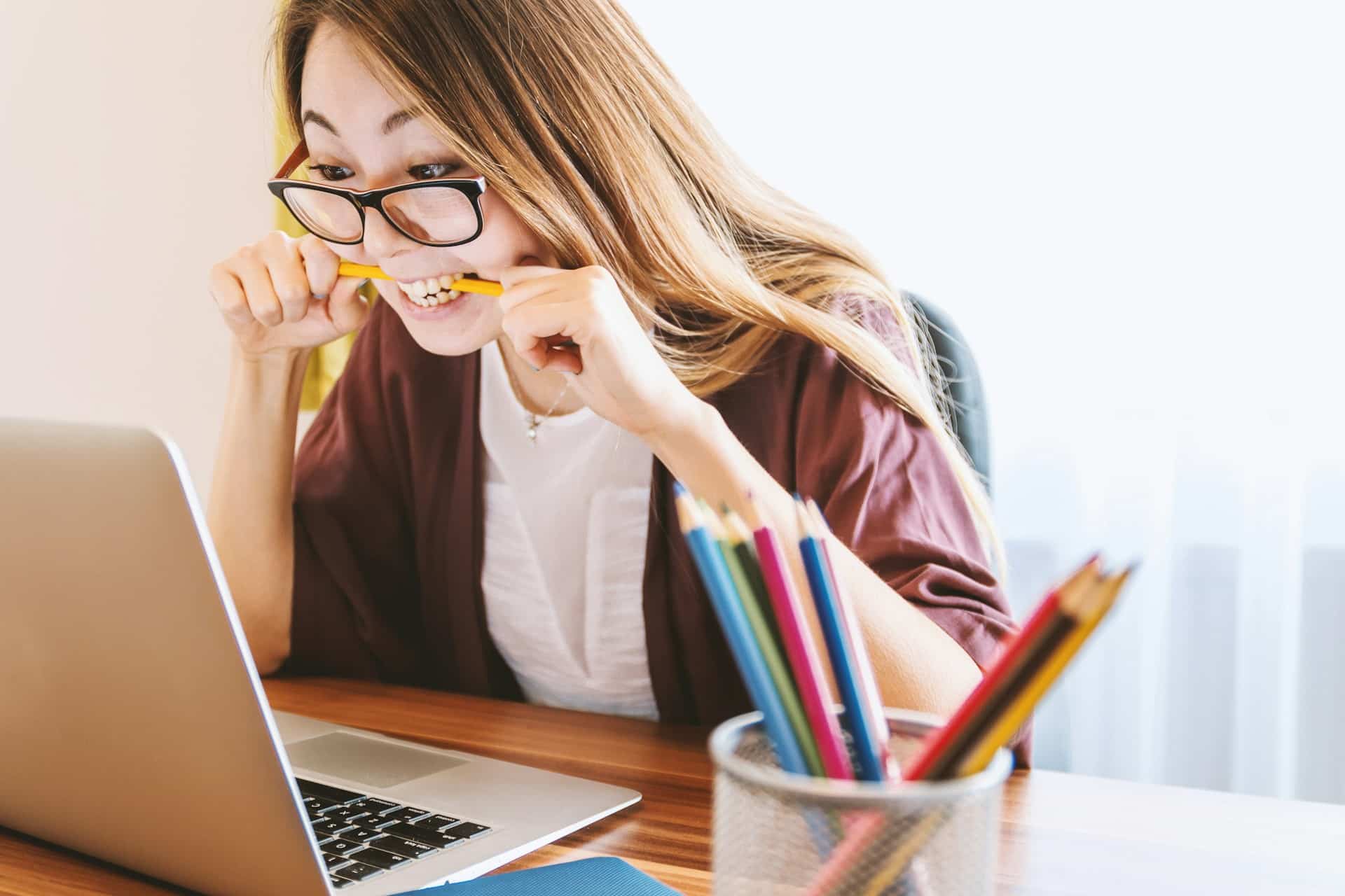 A woman biting a pencil caused by stress or extreme emotion like anger.